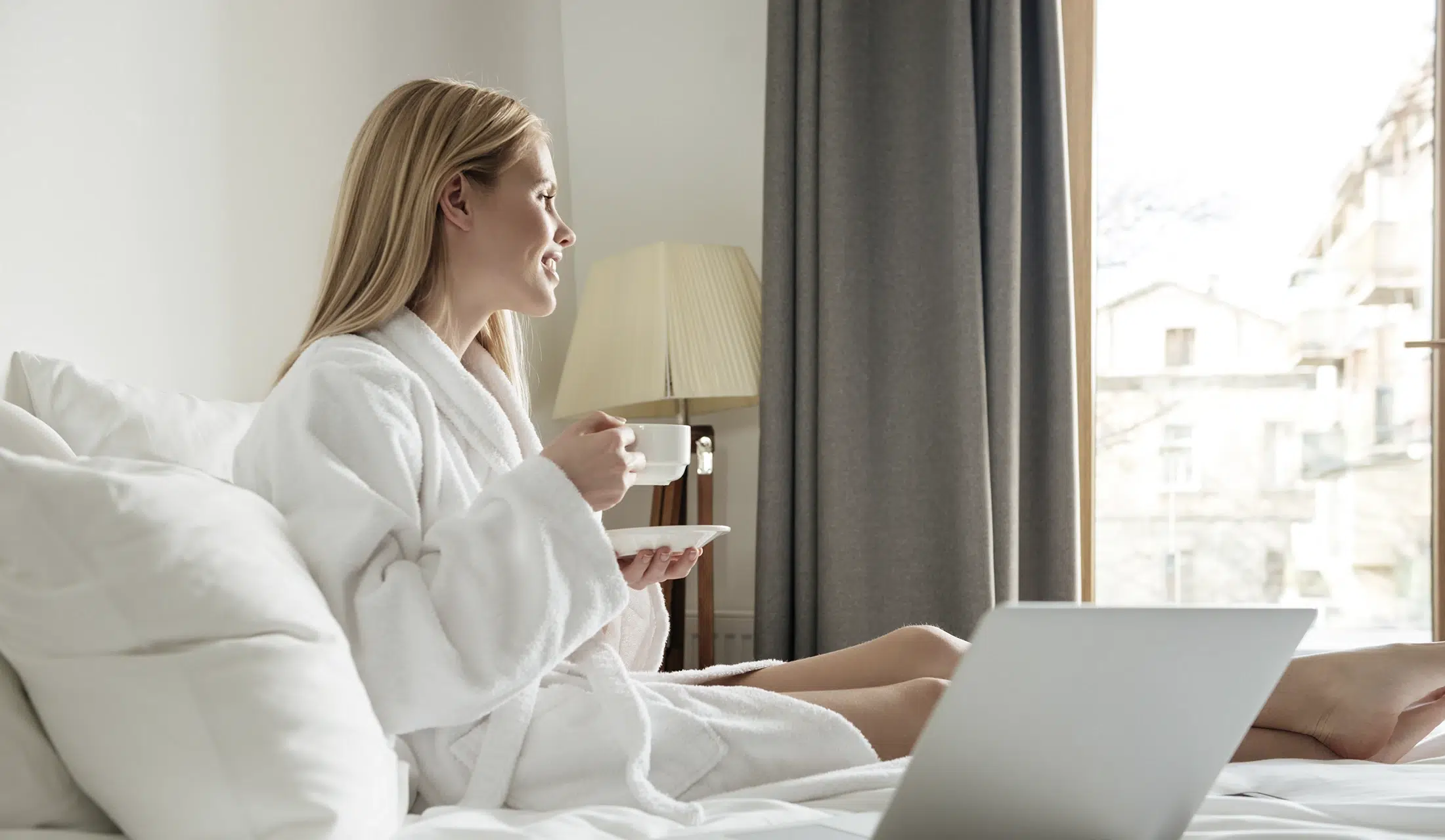 zufriedener Gast trinkt seinen morgendlichen Kaffee auf dem Bett